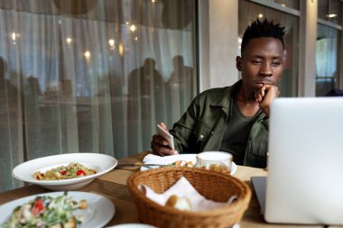 Genç Afro-Amerikan adam dizüstü bilgisayar kullanıyor.