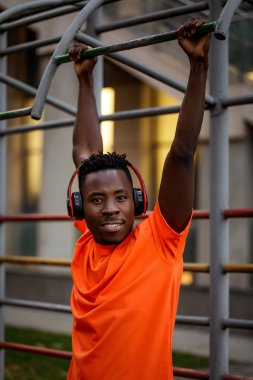 Afro-Amerikalı adam kendini yatay çubuklara çekiyor.