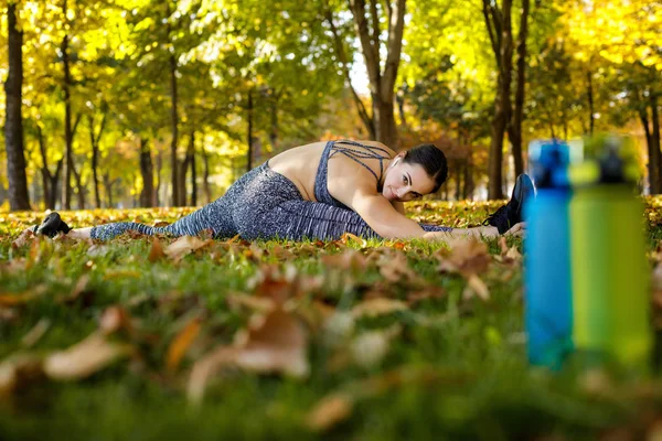 Donna sportiva che si estende su erba verde nel parco — Foto Stock