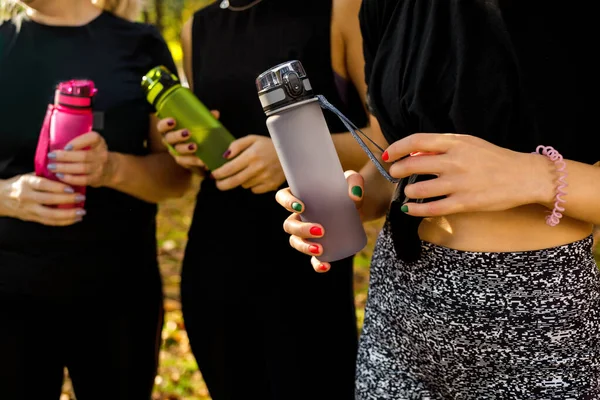 Mujeres deportivas de pie junto con botellas de agua después de hacer ejercicio — Foto de Stock