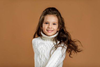 Kameraya bakan beyaz kazaklı küçük kız.