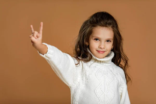 Liten barn flicka i vit tröja gör Rock gest — Stockfoto