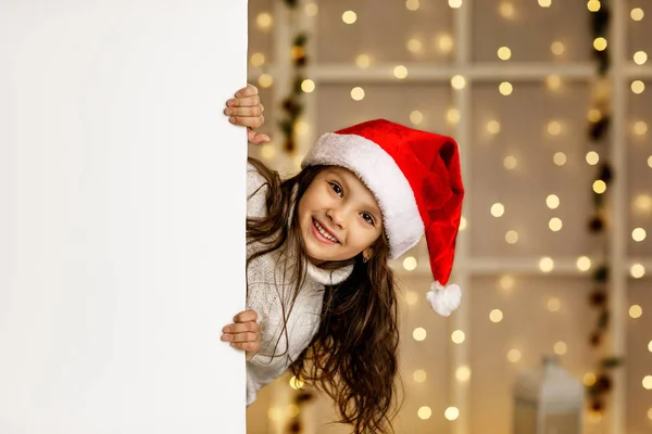 Little child girl in red santa hat holding white banner — Stock Photo, Image