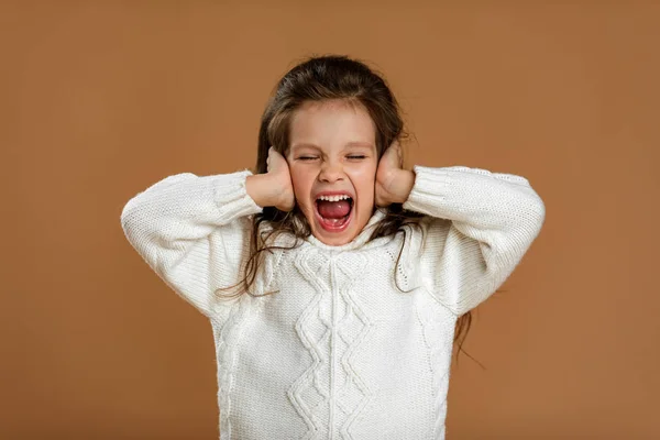 Söt lockig liten flicka i vit tröja stänger öronen — Stockfoto