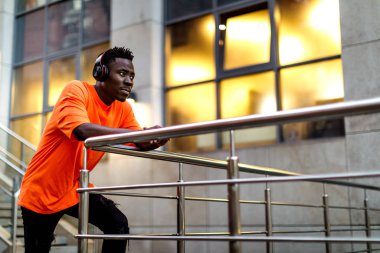 Kablosuz kulaklıklı, müzik dinleyen Afro-Amerikan bir adam.