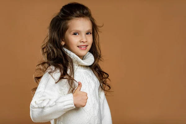 Bambina in maglione bianco che mostra i pollici in su — Foto Stock
