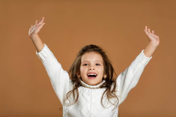 Petite fille souriante en pull blanc levant les mains vers le haut — Photo