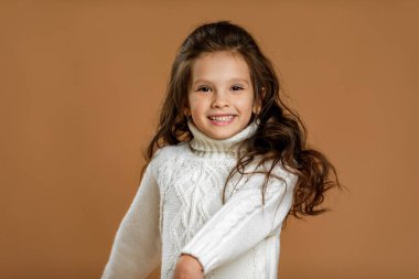 Kameraya bakan beyaz kazaklı küçük kız.