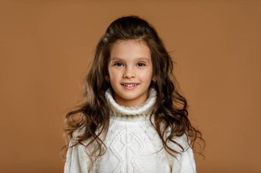 Kameraya bakan beyaz kazaklı küçük kız.