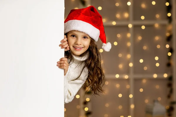 Little child girl in red santa hat holding white banner — Stock Photo, Image