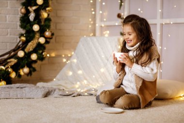 Sevimli küçük kız sıcak çikolata içiyor.