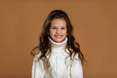 Kameraya bakan beyaz kazaklı küçük kız.