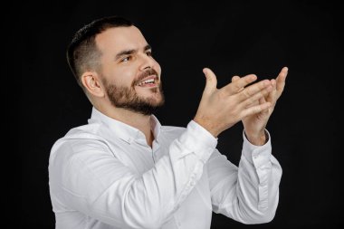 Beyaz gömlekli sakallı adam bir şey söylüyor.