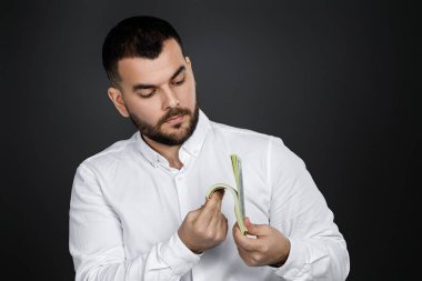 Sakallı adam elinde para banknotları tutuyor.