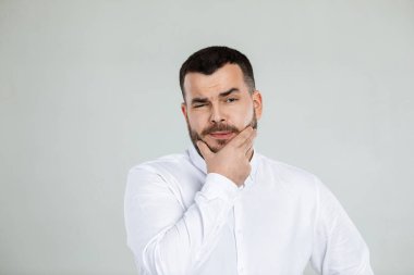 Gri arka planda sakallı şüpheli bir adam.