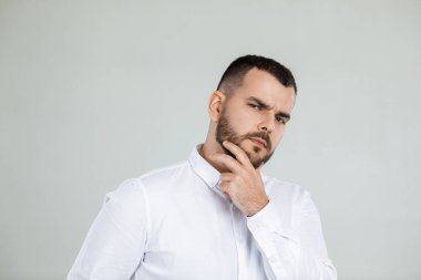 Gri arka planda sakallı şüpheli bir adam.