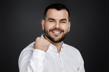 Genç, yakışıklı, sakallı adam yumruğunu kaldırıyor.