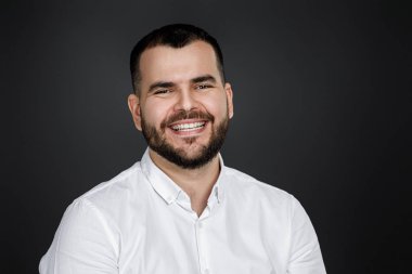 Gülümseyen yakışıklı sakallı adamın yakın plan portresi.