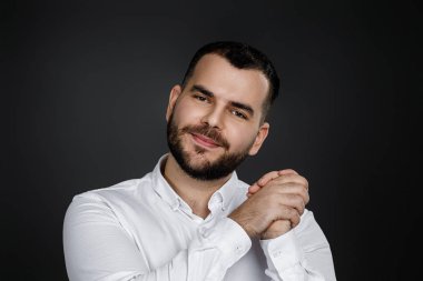 Genç, yakışıklı, sakallı adam yumruğunu kaldırıyor.