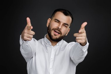 Yakışıklı, gülümseyen genç adam siyah arka planda sana işaret ediyor..