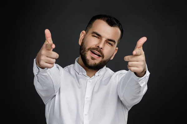 Knappe glimlachende jonge man wijst hand naar je op zwarte achtergrond. — Stockfoto