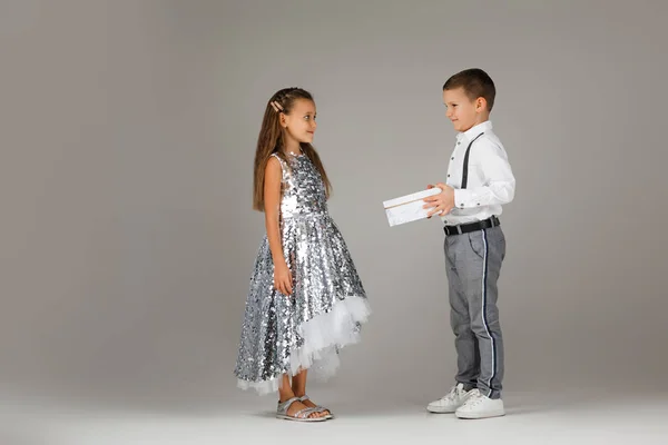 Pequeño niño dando caja de regalo a la niña de moda — Foto de Stock