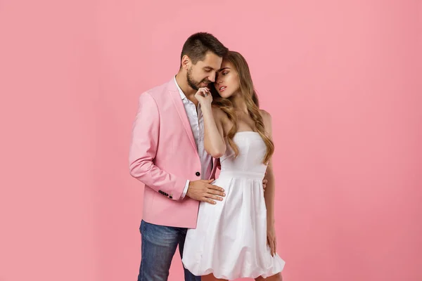 Lyckligt par i kärlek omfamna på rosa bakgrund. Alla hjärtans dag — Stockfoto