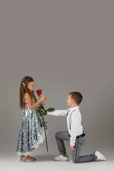 Pequeño niño dando una rosa roja a niña — Foto de Stock