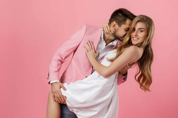 Pembe arka planda birbirini kucaklayan mutlu çift. Aziz Sevgililer Günü