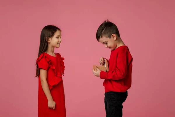 Joyeux petit garçon enfant donne une boîte cadeau à la fille souriante — Photo