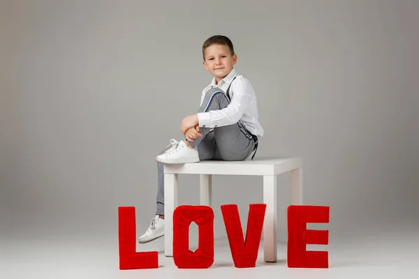 Kind jongen zitten in de buurt van rode woord brieven liefde — Stockfoto