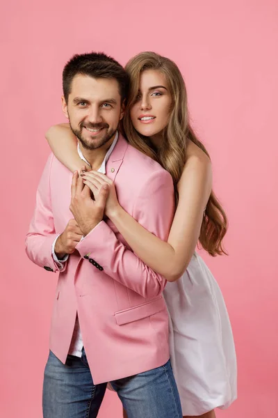 Lyckligt par i kärlek omfamna på rosa bakgrund. Alla hjärtans dag — Stockfoto