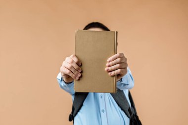Sırt çantalı küçük neşeli okul çocuğu kitap veriyor.