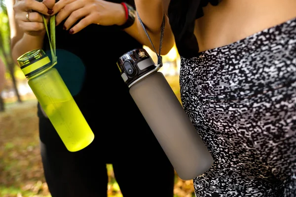 Mujeres deportivas de pie junto con botellas de agua después de hacer ejercicio — Foto de Stock