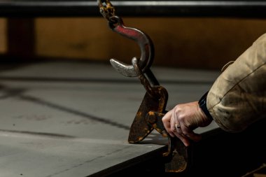 Sanayi işçisi vinçten kancalarla bir fabrikada çalışıyor.