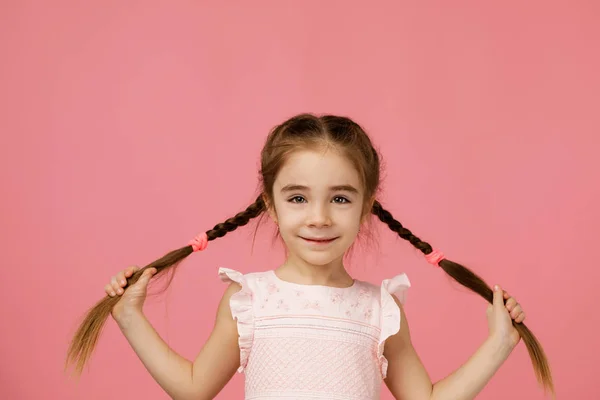 Küçük şirin kız uzun saç örgüleri tutuyor. — Stok fotoğraf