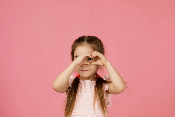Süßes lächelndes kleines Mädchen macht herzförmige Geste — Stockfoto