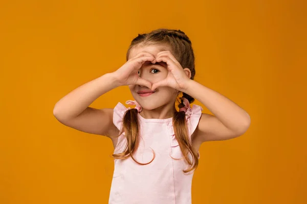 Słodkie uśmiechnięte małe dziecko dziewczyna co serce kształt gest — Zdjęcie stockowe