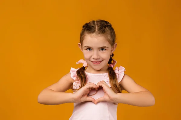 Słodkie uśmiechnięte małe dziecko dziewczyna co serce kształt gest — Zdjęcie stockowe