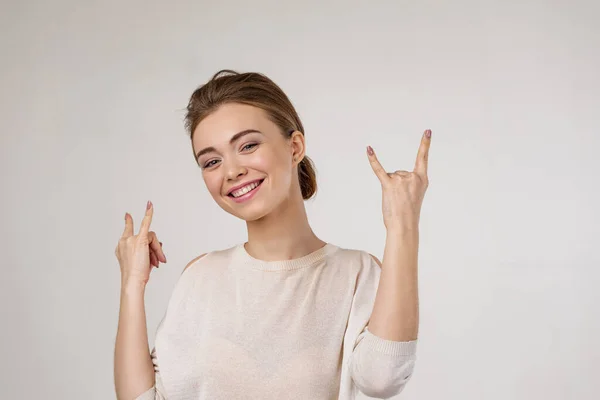 Улыбающаяся молодая женщина показывает рок-н-ролл руку — стоковое фото