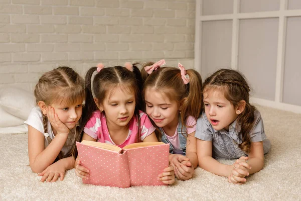 Bir grup çocuk yere yatıp masal kitabı okuyor. — Stok fotoğraf