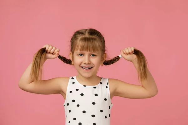 Petite fille mignonne tenant des tresses à cheveux longs — Photo