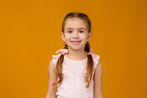 Милая улыбающаяся маленькая девочка смотрит в камеру — стоковое фото