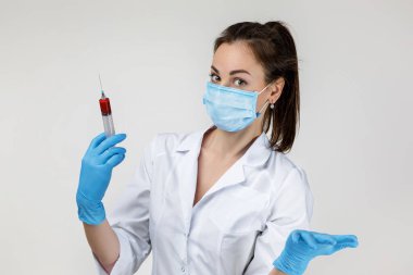woman doctor in mask and rubber gloves holding syringe