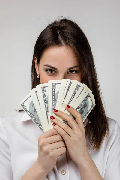 Mujer con camisa blanca escondida detrás de un montón de billetes de dinero — Foto de Stock