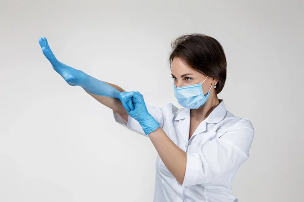 Woman doctor in white uniform wearing mask and rubber gloves — Stockfoto