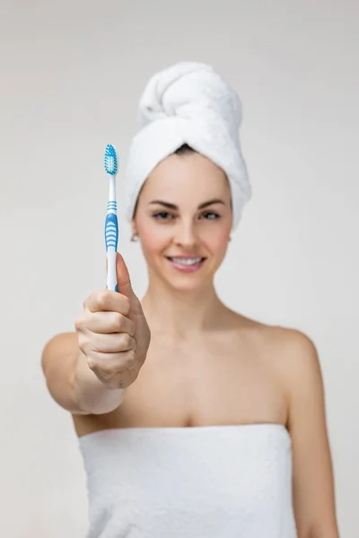 Happy young woman in towel showing toothbrush. — Stockfoto
