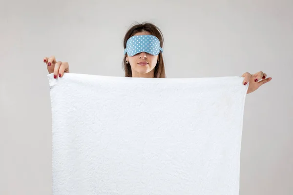 Young caucasian woman in eyemask holding towel — Stockfoto