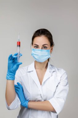woman doctor in mask and rubber gloves holding syringe
