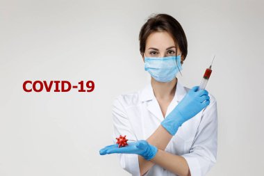 Kadın doktor elinde şırınga ve virüs modeli tutuyor.